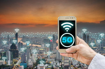 Mobile network connection technology concept, 5G network digital mobile phone and wifi icon on city background, businessman holding phone and icon 5g on city background.