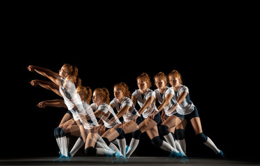 Young female volleyball player isolated on black studio background. Woman in sport's equipment and...