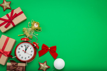 Red alarm clock, Christmas decorations, Christmas toys and gift boxes on a green background. The concept of Merry Christmas and New Year. Flat lay, top view. Copy space