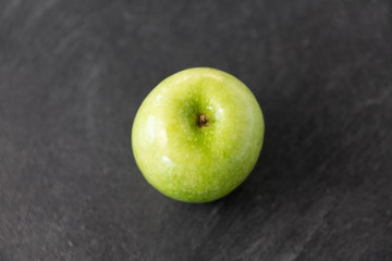 fruits, diet, eco food and objects concept - ripe green apple on slate stone background