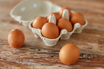 food, culinary and cooking concept - close up of natural chicken eggs in cardboard box on wooden table