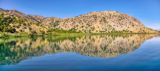 Panorama of natural freshwater lake Kournas near Georgioupolis, the White Mountains reflected in the water, Crete, Greece