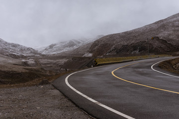 Country road winding through a valley surrounded by snowy mountains