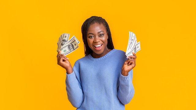 Happy afro girl with dollar cash over yellow background