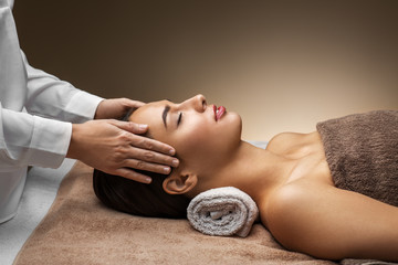 Obraz na płótnie Canvas wellness, beauty and relaxation concept - beautiful young woman lying with closed eyes and having face and head massage at spa