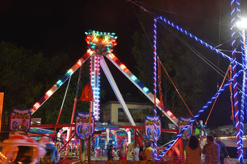 Beautiful carousels at night, colorful lights, people walk and enjoy.