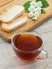 Glass cup of tea, bread and white jasmine flowers