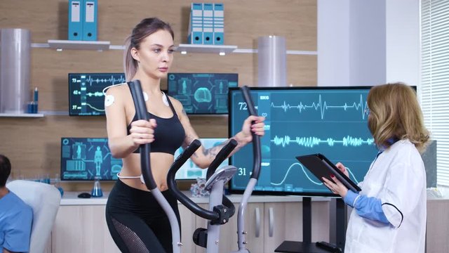 Female athlete runs on treadmill with electrodes attrached on her body
