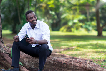 Obraz premium African man reading a book in the park.