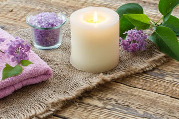 Obraz na płótnie Canvas Towel, sea salt, candle and lilac flowers on wooden background.