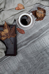 Cup of black coffee with chocolate cookies surrounded by autumn leaf and notebook on a wooden table