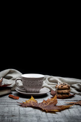 Cup of black coffee with chocolate cookies surrounded by autumn leaf and notebook on a wooden table