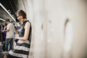 Portrait of Asian young short hair beautiful woman wearing glasses and grey dress in tunnel