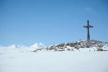Fototapeta na wymiar cross on icy mountain in the winter season under sky