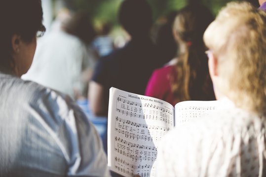 Selective focus shot from behind of people reading notes in the choir with a blurred background