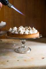 Lemon tart with french meringue caramelized on top, on a rustic table, french meringue caramelized with a food torch.