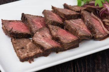 Plate with meat cutting and fresh greens on white plate