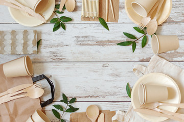 Eco friendly disposable dishes made of bamboo wood and paper on white wooden background.