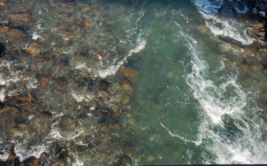 top view of a rocky channel and almost clear bluish-muddy water of a mountain river