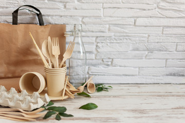 Eco friendly disposable dishes made of bamboo wood and paper on white wooden background.
