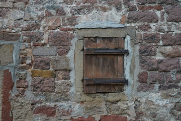 Kleines verschlossenes Fenster in einer alten steinernen Hauswand
