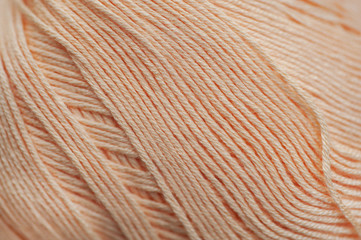 Skein of pastel peach- beige colored bamboo thread macro abstract background