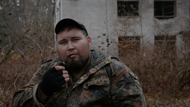 Man in camouflage smoking tabacco pipe