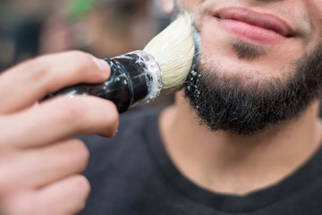 shaving a beard to a caucasian man. Lathers a beard, preparing it for a haircut. Barber Shop Professional Beard Care