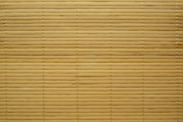 Mat of thin yellow bamboo sticks textured background