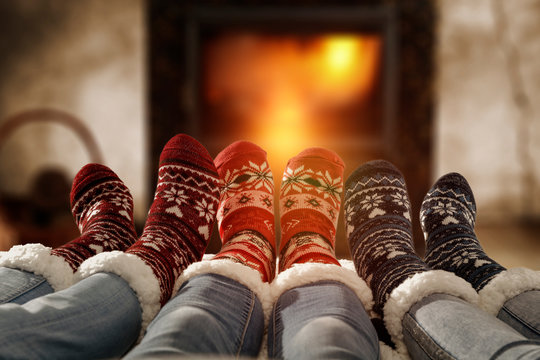 Woman Legs In Home Interior With Fireplace.Woolen Socks And Jeans.Free Space For Your Decoration.Christmas Cold Winter Night.Copy Space. 