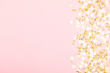 Obraz premium Christmas modern composition. Golden decorations, confetti, stars on pastel pink background. Christmas, New Year, winter concept. Flat lay, top view, copy space