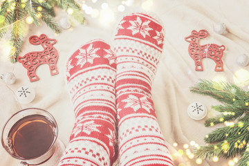 feet in Christmas socks, garlands, toys, lights. cozy tea party on Christmas holidays.