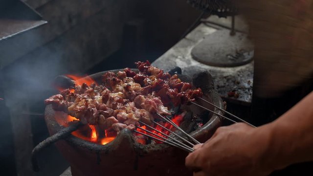 Burn lamb meat on charcoal stove close up view with bicycle metal spokes, known as Sate Klatak
