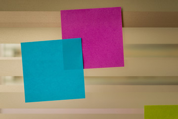 Colored sticky notes over glass screen of a bench desk