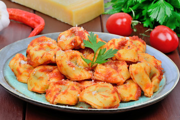 Tortellini with tomatoes sauce in a plate on a table