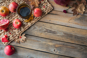 Glass of red wine, apples, grapefruits, autumn leaves and flowers on a wooden table