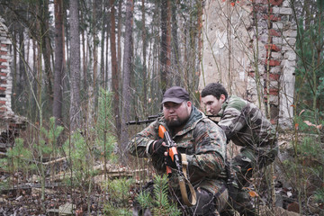 Two armed soldiers move around the destroyed building