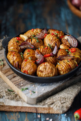 Baked potatoes in cast-iron pan with onion, garlic and herbs. Dish for dinner. Close up view. 