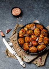 Baked potatoes in cast-iron pan with onion, garlic and herbs. Dish for dinner. Close up view. 