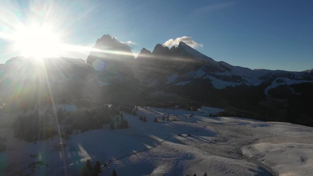Aerial view of mountains with snow at sunrise - Backlight panoramic video of Dolomites in winter with snow on the valley - Nature and travel concepts