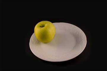 minimalist photography with golden apple on white plate isolated on black background