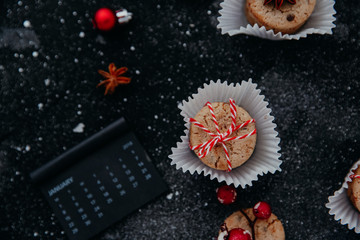 Flat lay Christmas composition with cookies, calendar on black background. Top view with copy space.Sweet xmas or new year gift