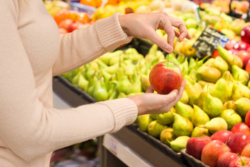 Female hand choosing apple in the store. Concept of healthy food, bio, vegetarian, diet.