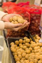 Female hand choosing walnuts in the store. Concept of healthy food, bio, vegetarian, diet.