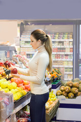 Obraz premium Woman choosing a dairy products at supermarket. Reading product information