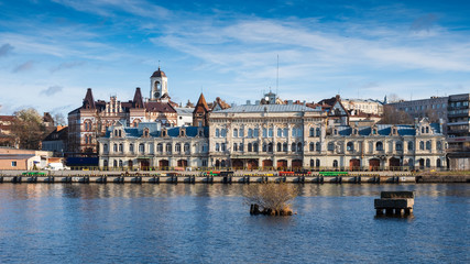 Fototapeta na wymiar Panorama of the embankment with ancient beautiful buildings of the city of the middle-century city of Vyborg in Russia on an autumn sunny day