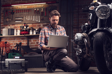 Mechanic checking data on a laptop in a workshop - 302268373