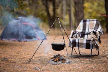 Relaxing and preparing food on campfire in camping, autumn rest outdoors in forest