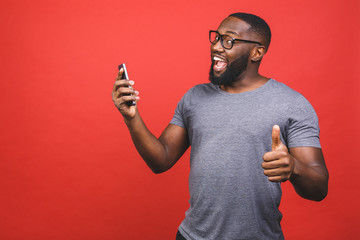 Afro american man using smartphone over isolated red background happy with big smile doing ok sign,...