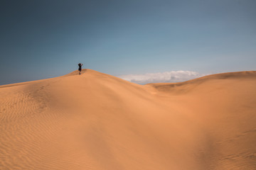 Fototapeta na wymiar girl on the horizon walks the dunes